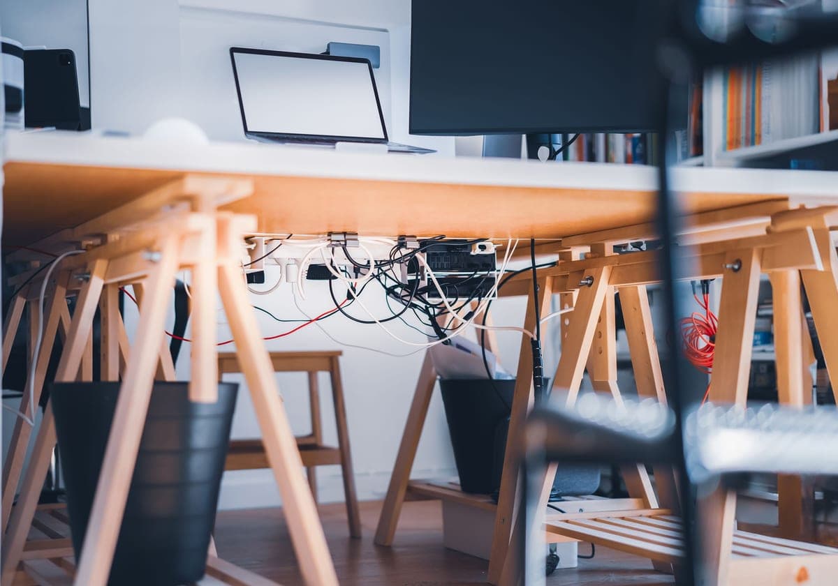 Cables routed neatly into a tray beneath a desk, gathered into a single sleeve