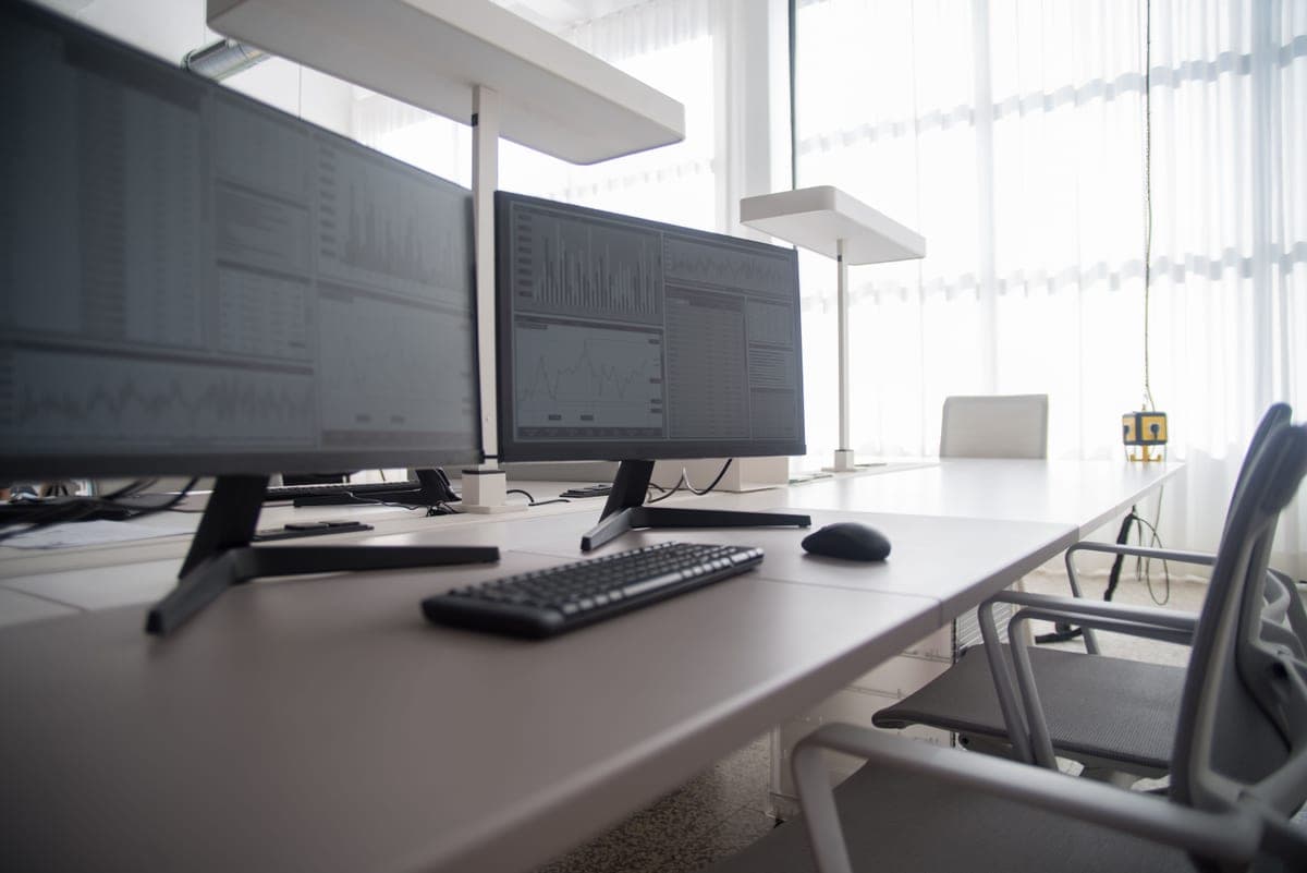 A monitor held on an articulating arm above a clear desk, with the arm's joints visible