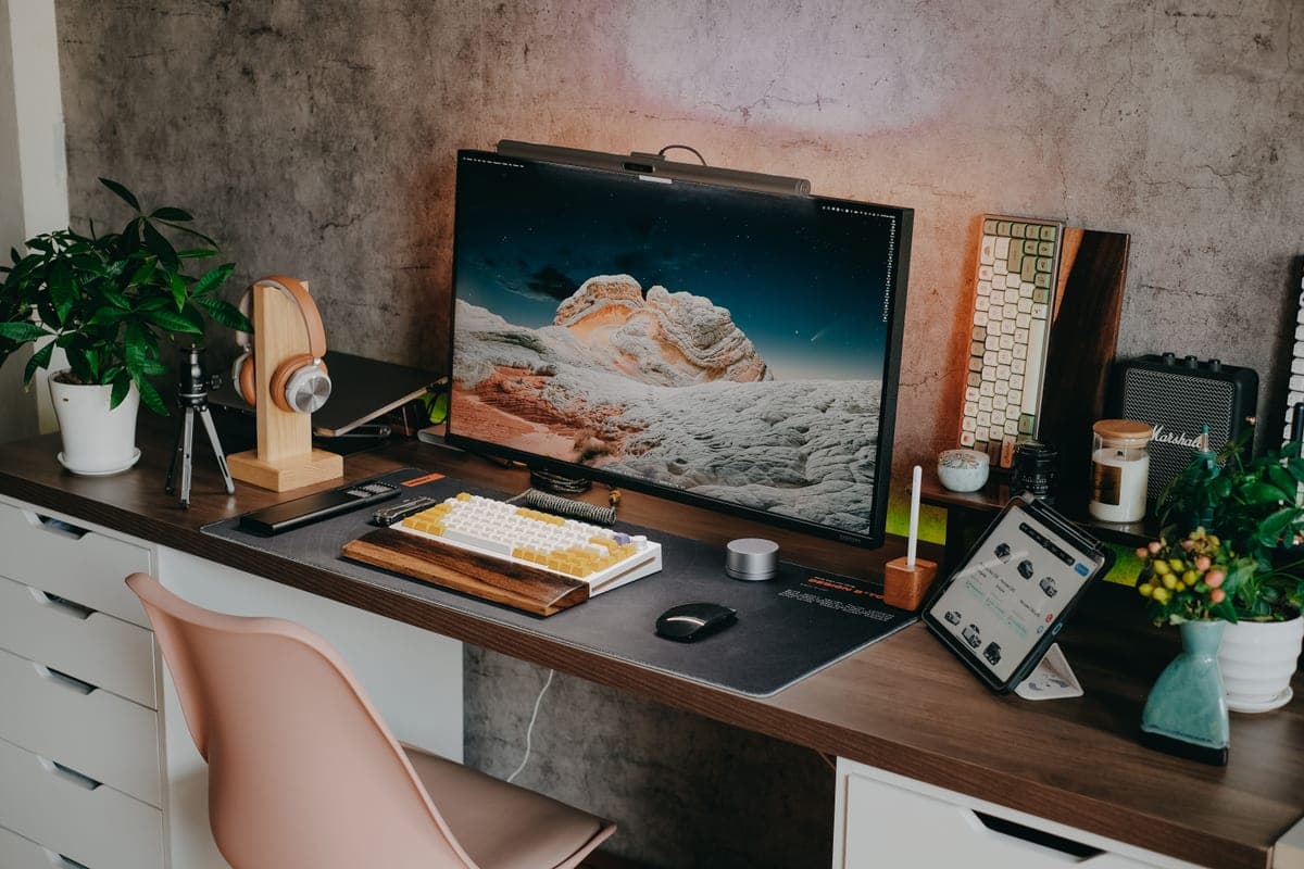 A well-arranged home office desk seen from the side, showing monitor height relative to a seated eyeline