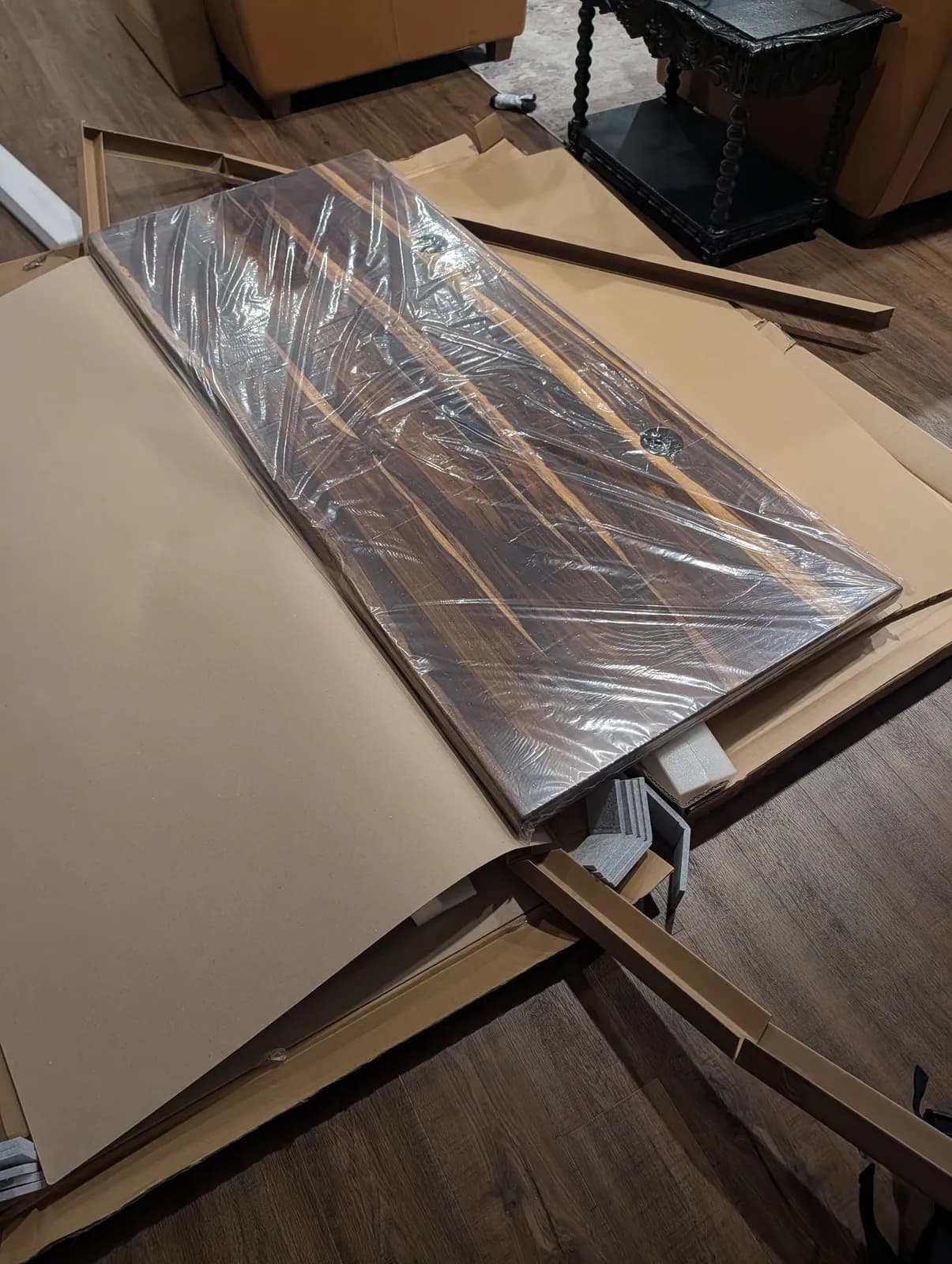 The Pheasantwood top still sealed in its plastic wrap, lifted clear of the box, its dark striped grain showing through.