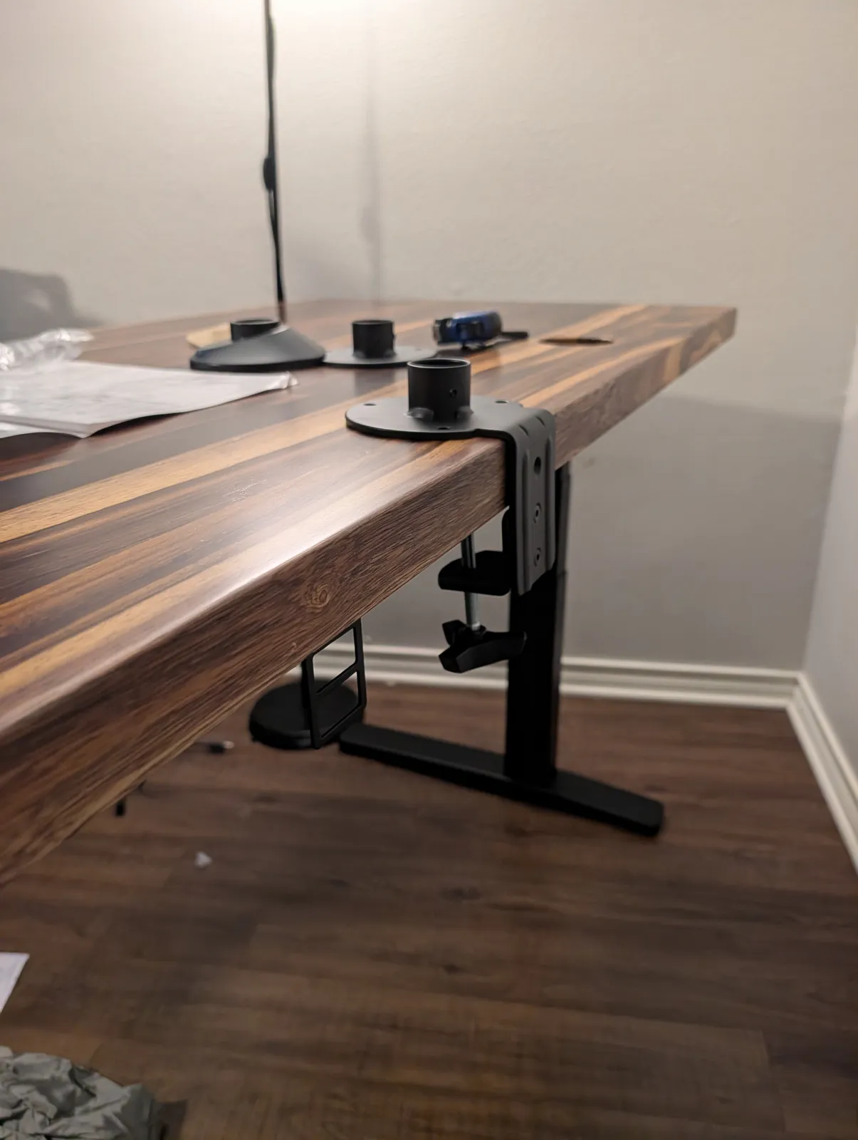 The finished top standing on its frame, with the monitor arm's bolt-through mount clamped through the back edge and its round collar base sitting on the desktop.
