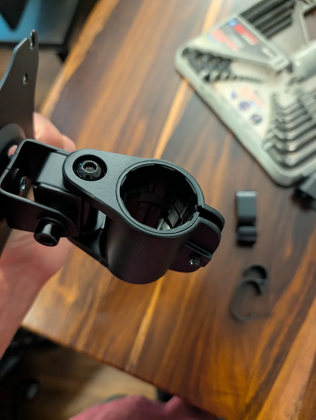 A monitor arm collar held in one hand with the bore facing the camera, so the clamping insert inside it is visible.