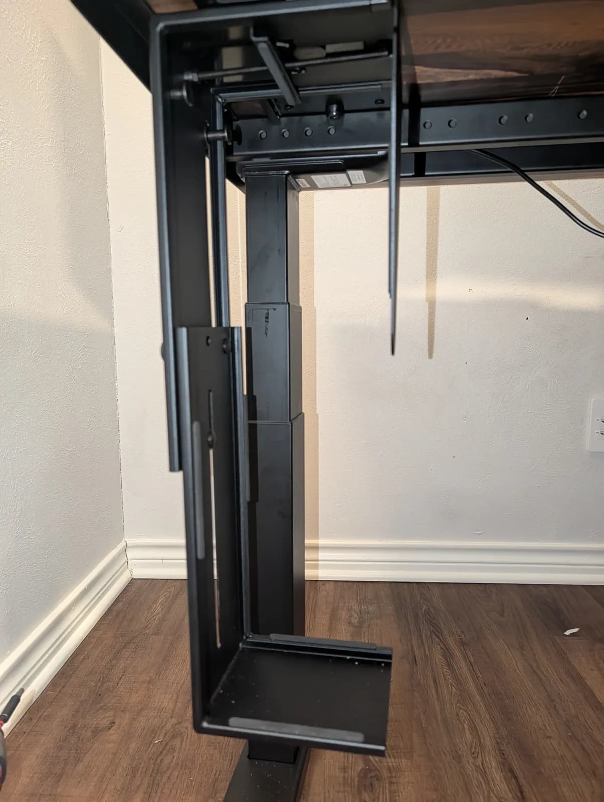 The CPU holder bolted under the desk and hanging empty, its slide-out track above and its two side rails open at the bottom.
