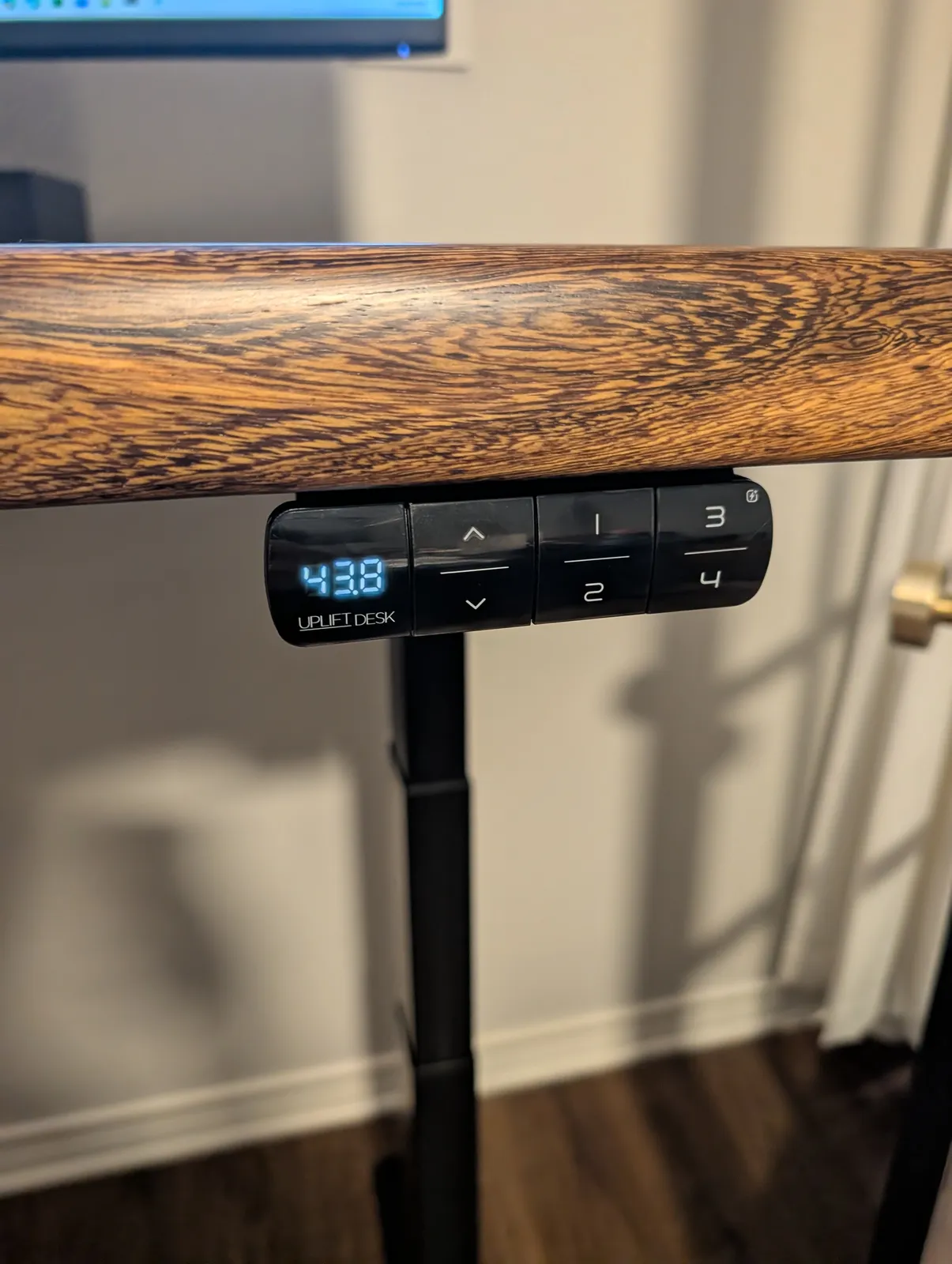 The Advanced Keypad under the front edge of the desk, reading 43.8 on its display, with up and down arrows and four preset buttons.