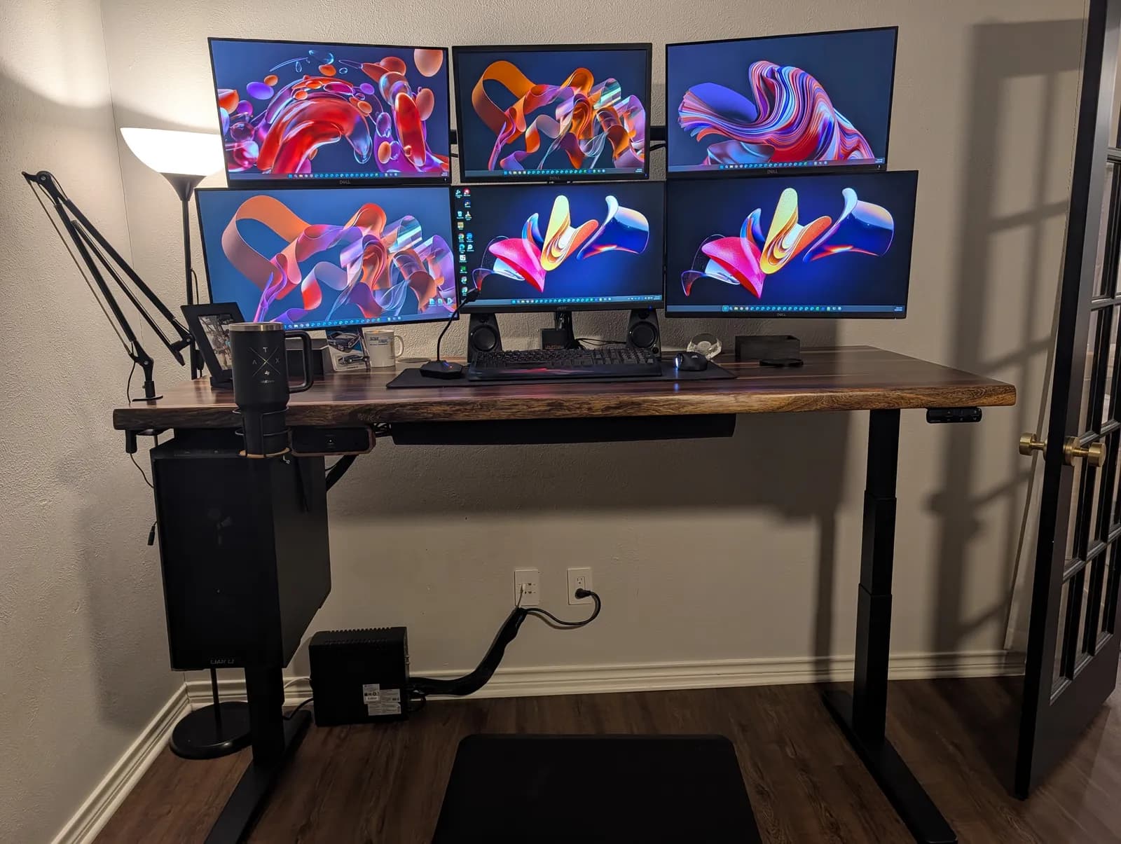 The finished desk at standing height: six monitors in two rows on the Moontower arm, keyboard and desk pad on the Pheasantwood top, the tower hanging on the CPU holder at the left and the standing mat on the floor.